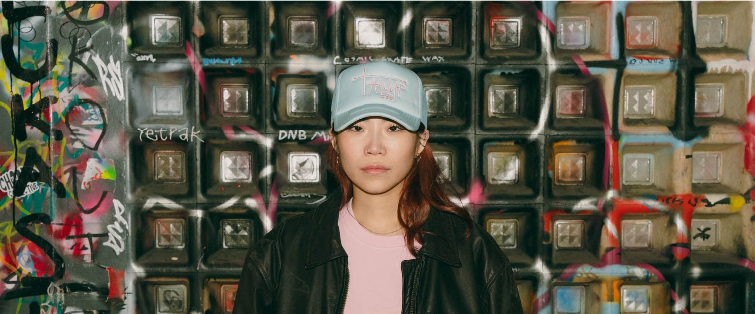 Tamp Coffee new collection december 2023 the picture shows a woman wearing a light blue trucker cap and a pink tee